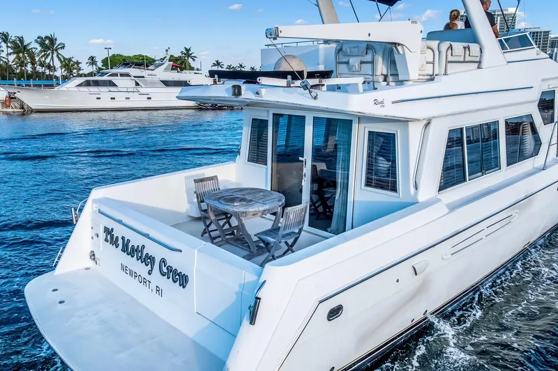 Motely Crew Yacht Photos Pics 2003 Navigator Rival 5700 yacht cruising on blue waters near palm trees.