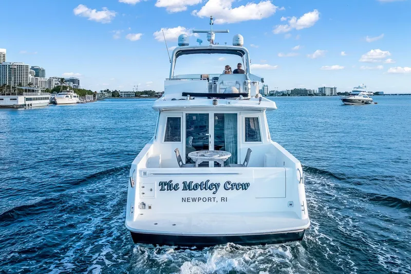 Motely Crew Yacht Photos Pics Navigator Rival 5700 yacht cruising in Newport, RI, with cityscape and blue sky.