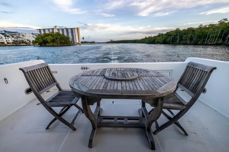 Motely Crew Yacht Photos Pics Deck view from 2003 Navigator Rival 5700 yacht with wooden table and chairs, overlooking serene waterway.