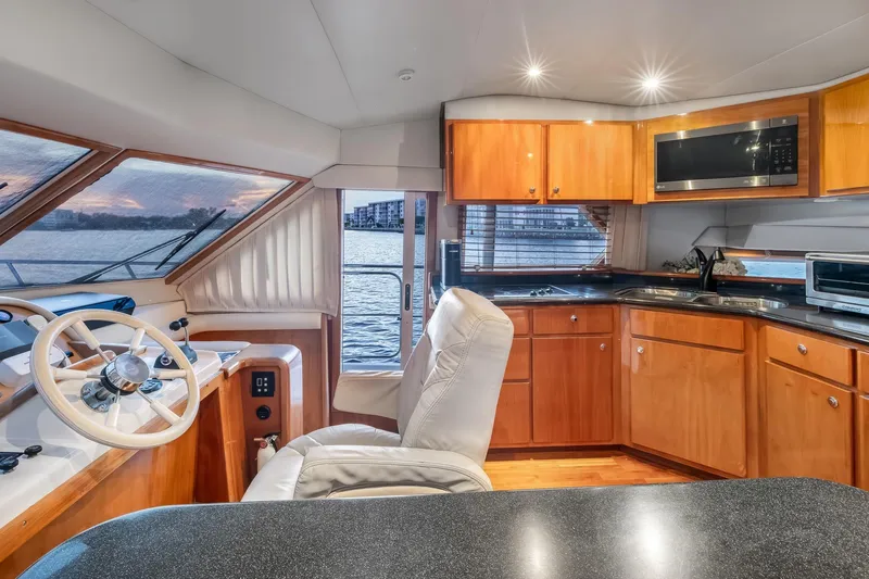 Motely Crew Yacht Photos Pics Luxurious 2003 Navigator Rival 5700 yacht interior with helm, kitchen, and waterfront view.