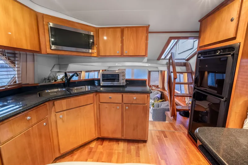Motely Crew Yacht Photos Pics Luxurious kitchen interior of 2003 Navigator Rival 5700 yacht with wooden cabinetry.