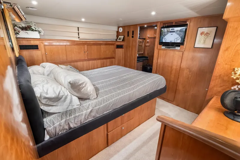 Motely Crew Yacht Photos Pics Luxurious bedroom interior of 2003 Navigator Rival 5700 yacht with wood paneling and TV.