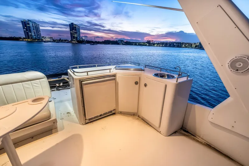 Motely Crew Yacht Photos Pics Luxury yacht deck with kitchenette, overlooking serene waterfront at sunset, Navigator Rival 5700, 2003.