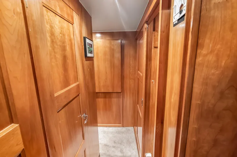 Motely Crew Yacht Photos Pics Wood-paneled hallway inside 2003 Navigator Rival 5700 yacht, featuring elegant doors and soft lighting.