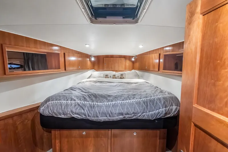 Motely Crew Yacht Photos Pics Luxurious bedroom interior of 2003 Navigator Rival 5700 yacht with wood paneling and skylight.