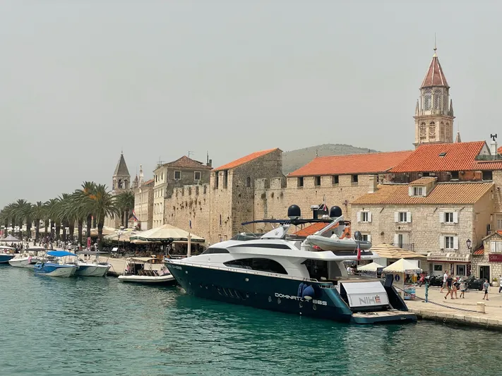 Nike Yacht Photos Pics Luxury yacht Dominator 860 (2007) docked by historic waterfront with palm trees and stone buildings.