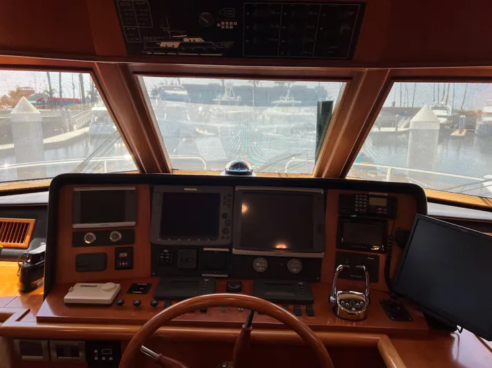 Off Line Yacht Photos Pics Boat cockpit with navigation equipment, steering wheel, and marina view; Symbol PHMY 2007 model.