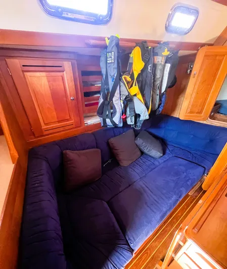  Yacht Photos Pics Cozy interior of 2003 Tartan 4100 sailboat with blue seating and hanging jackets.