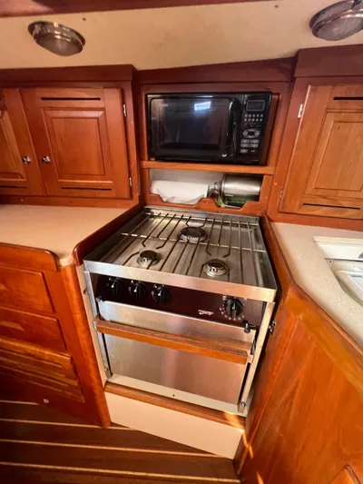  Yacht Photos Pics 2003 Tartan 4100 yacht kitchen with stove, microwave, and wooden cabinetry.