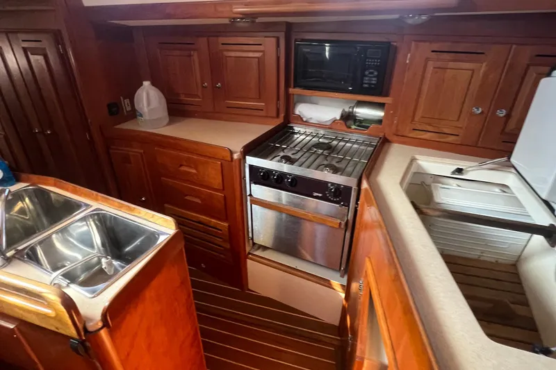  Yacht Photos Pics 2003 Tartan 4100 yacht kitchen with wood cabinetry, stainless steel sink, and stove.