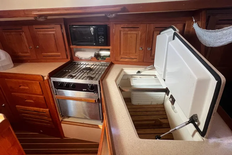  Yacht Photos Pics 2003 Tartan 4100 yacht kitchen with stove, microwave, and wooden cabinets.