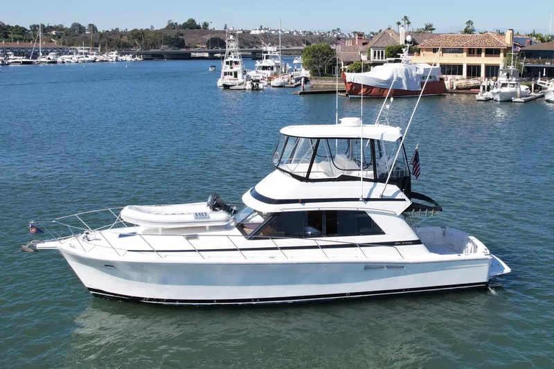 Seafood (reserved) Yacht Photos Pics 1998 Riviera 43 Open Flybridge yacht on calm waters near a marina.