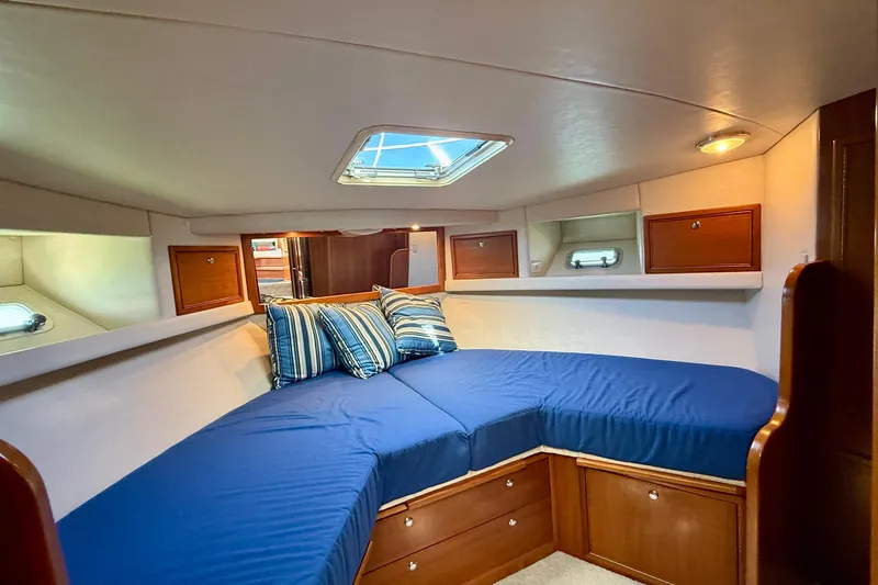 Seafood (reserved) Yacht Photos Pics 1998 Riviera 43 Open Flybridge cabin with blue bedding and wooden storage cabinets.