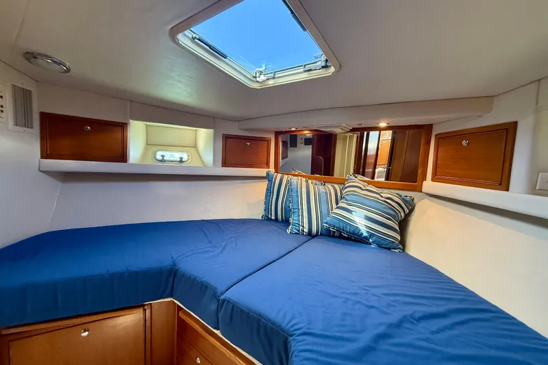 Seafood (reserved) Yacht Photos Pics Cozy cabin interior of 1998 Riviera 43 Open Flybridge with blue bedding and striped pillows.