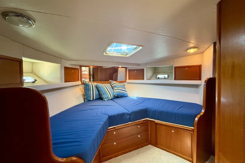 Seafood (reserved) Yacht Photos Pics Cozy cabin interior of 1998 Riviera 43 Open Flybridge with blue bedding and wooden storage.