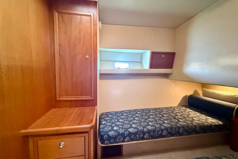 Seafood (reserved) Yacht Photos Pics 1998 Riviera 43 Open Flybridge cabin with wooden cabinetry and patterned bedding.
