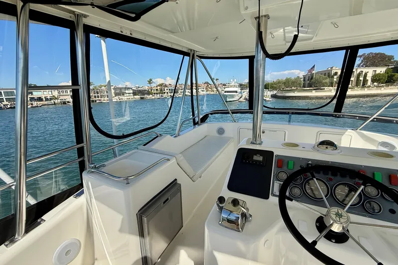 Seafood (reserved) Yacht Photos Pics 1998 Riviera 43 Open Flybridge helm with waterfront view, showcasing controls and seating.