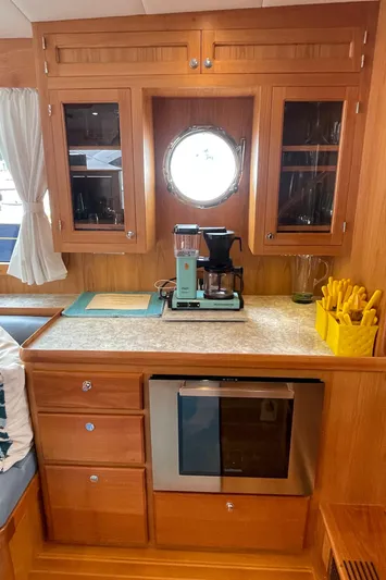 Sherlock Holmes Yacht Photos Pics Kadey-Krogen 44E 2016 yacht galley with wooden cabinets, porthole, and coffee maker.