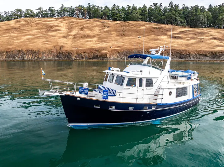 Sherlock Holmes Yacht Photos Pics Kadey-Krogen 44E 2016 yacht on calm water, scenic background, for sale sign visible.