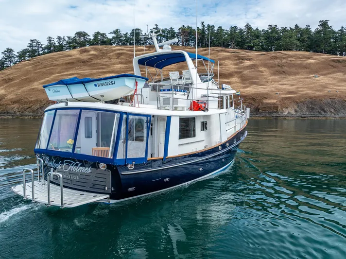Sherlock Holmes Yacht Photos Pics 2016 Kadey-Krogen 44E yacht cruising near a rocky shoreline with trees.