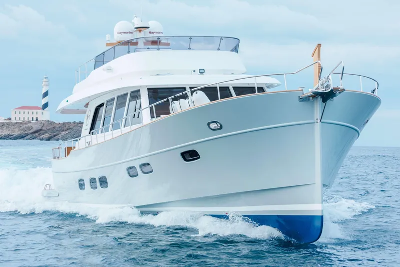  Yacht Photos Pics 2026 Sasga Yachts Menorquin 68 cruising near a lighthouse on a clear day.