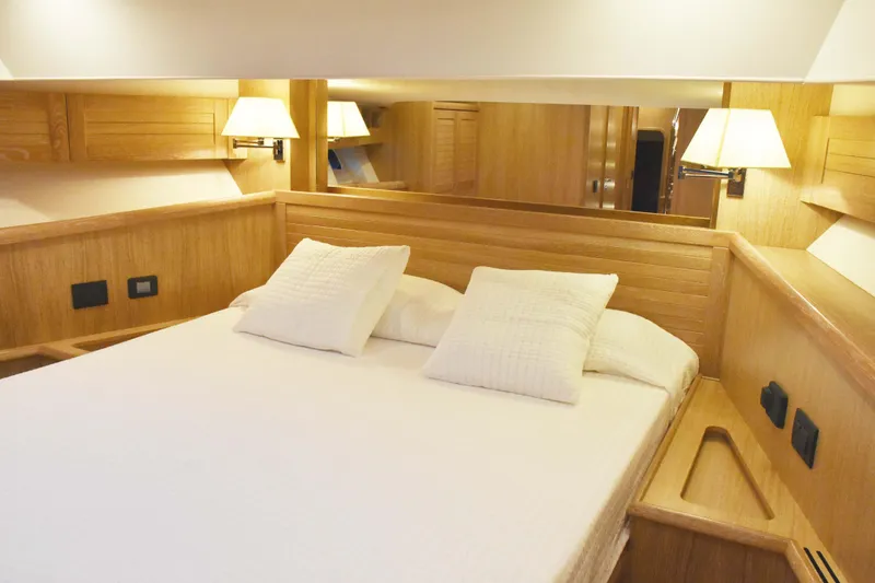  Yacht Photos Pics Luxurious cabin interior of 2026 Sasga Yachts Menorquin 68 with wooden finish and cozy bedding.