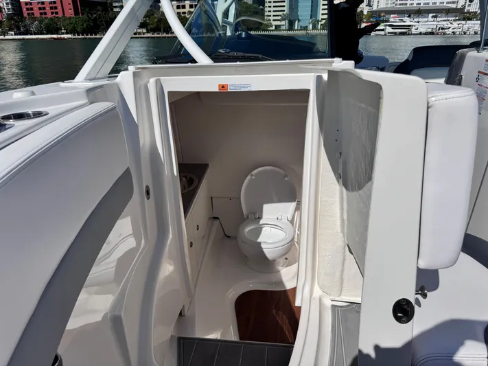  Yacht Photos Pics 2021 Robalo R317 Dual Console boat interior with compact marine toilet.