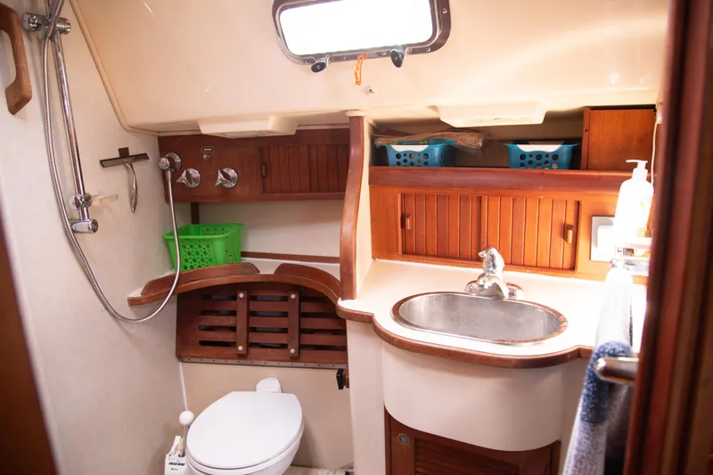 Harvest Moon Yacht Photos Pics Island Packet 380 yacht bathroom, 1999 model, featuring sink, toilet, shower, and wooden cabinetry.