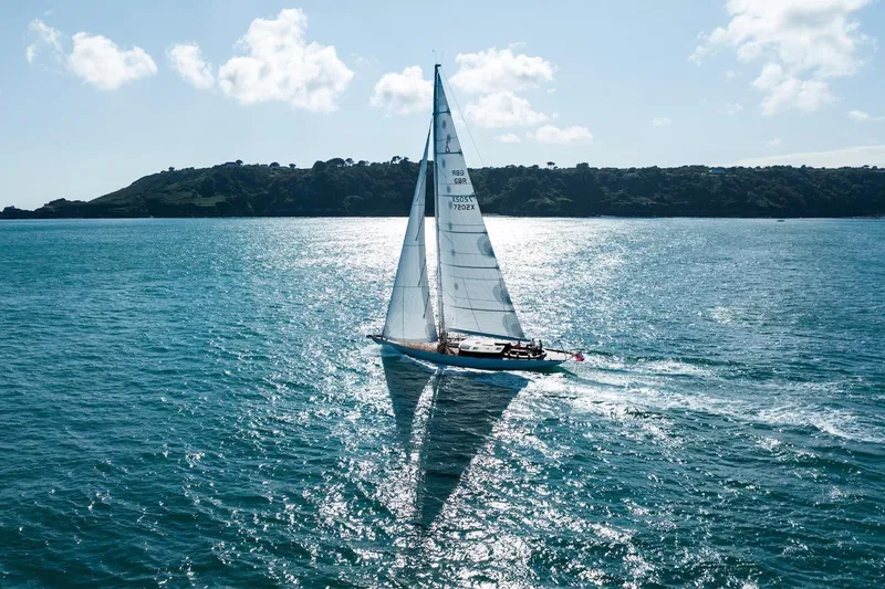 Gwenhyfar II Yacht Photos Pics Sailing yacht Spirit C72, 2023 model, gliding on sparkling blue water with scenic coastline.