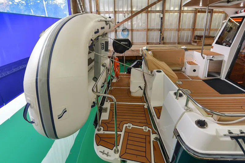 Celtic Mist Yacht Photos Pics 2023 Ranger Tugs R-29S boat with inflatable dinghy on deck, docked in a wooden boathouse.