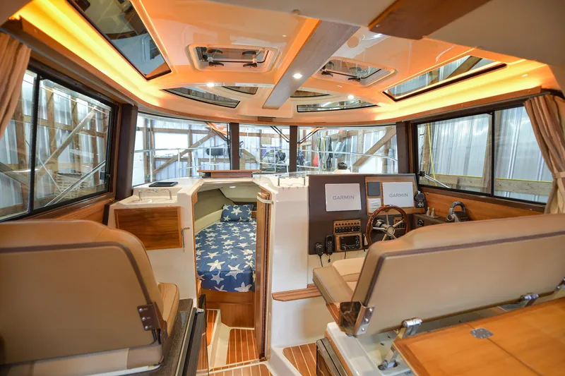 Celtic Mist Yacht Photos Pics 2023 Ranger Tugs R-29S interior with helm, seating, and star-patterned bedding.