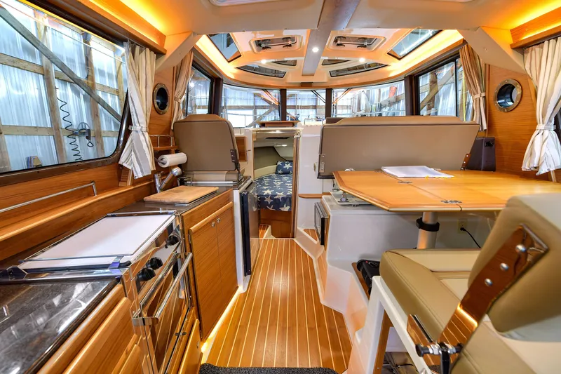 Celtic Mist Yacht Photos Pics 2023 Ranger Tugs R-29S interior with wood finish, kitchen, and seating area.