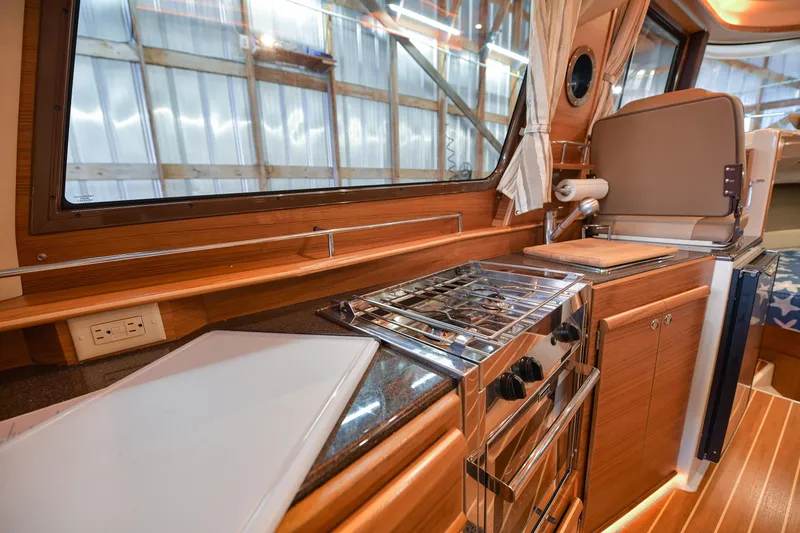 Celtic Mist Yacht Photos Pics 2023 Ranger Tugs R-29S interior kitchen with stove, cutting board, and wooden cabinetry.