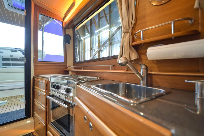 Celtic Mist Yacht Photos Pics 2023 Ranger Tugs R-29S interior kitchen with stove, sink, and wooden cabinetry.