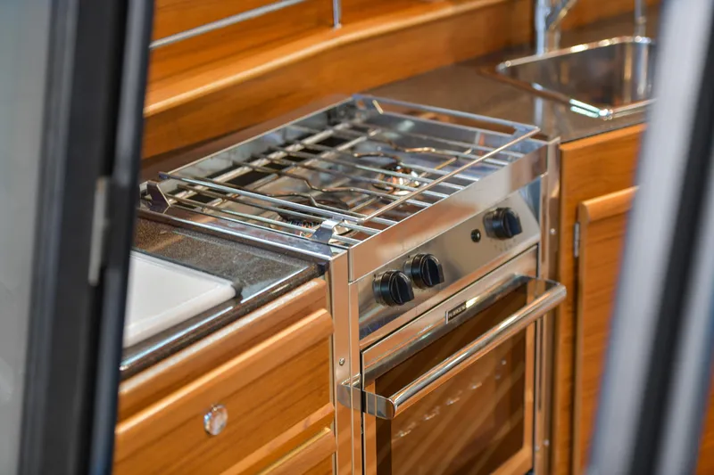 Celtic Mist Yacht Photos Pics 2023 Ranger Tugs R-29S kitchen with stainless steel stove and wooden cabinetry.