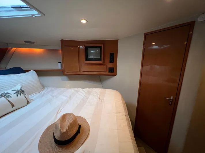 Todo Bien Yacht Photos Pics Cozy bedroom in 2000 Viking 58 Enclosed Bridge yacht with TV and straw hat on bed.
