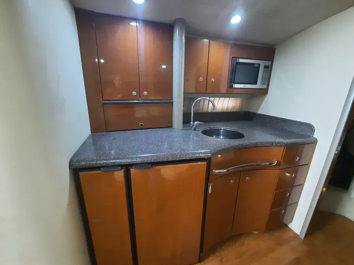 Paradox Yacht Photos Pics 2008 Formula 40 PC yacht kitchen with wooden cabinets, granite countertop, sink, and microwave.