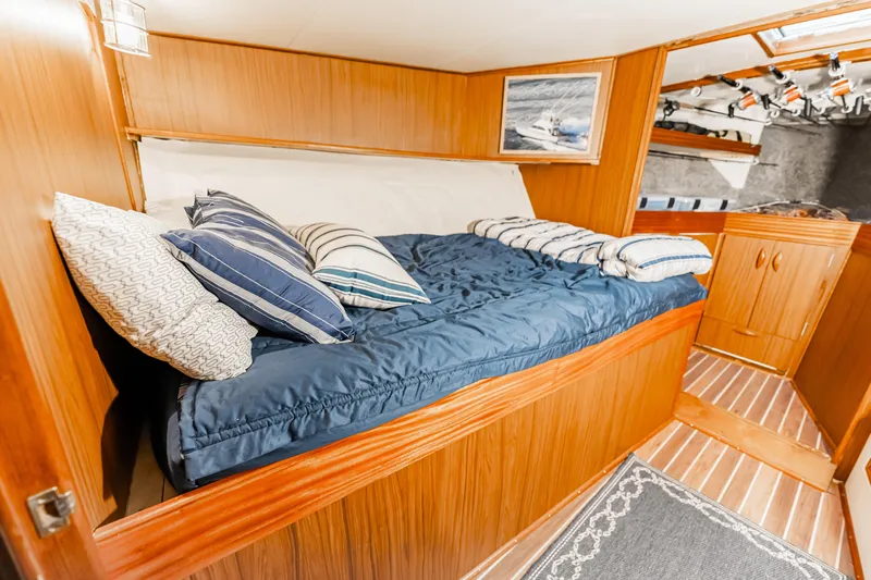 Leslie Ann Yacht Photos Pics Cozy cabin interior of 1988 Buddy Davis 47 Convertible yacht with wooden finish and striped bedding.