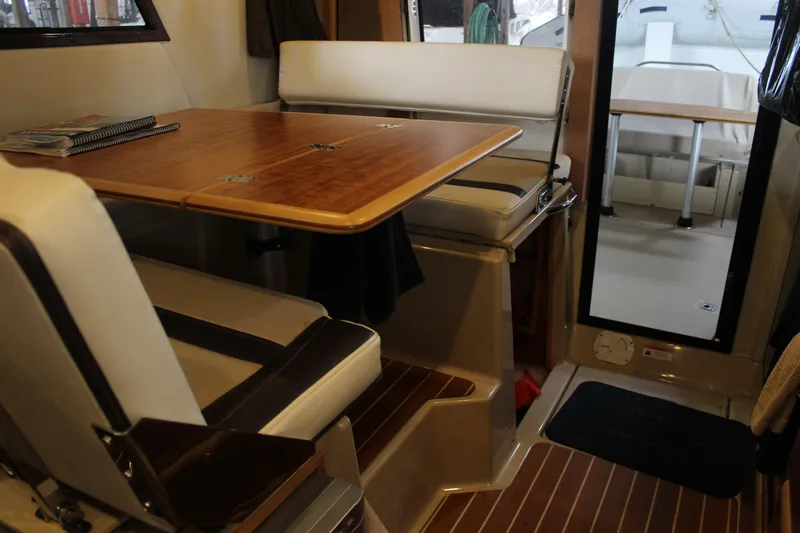  Yacht Photos Pics Interior of 2016 Cutwater 30 Command Bridge with wooden table and cushioned seating.