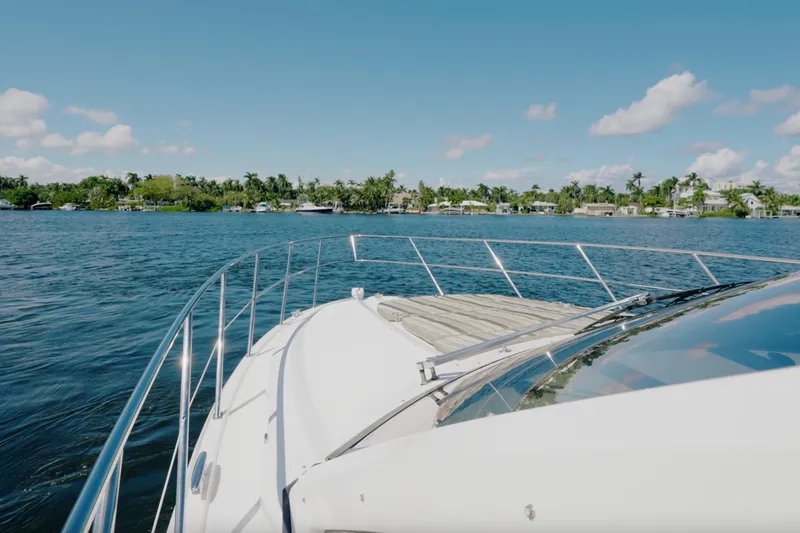 Life Is Good Yacht Photos Pics 2017 Regal 53 Sport Coupe yacht cruising on a sunny day, with waterfront homes in the background.