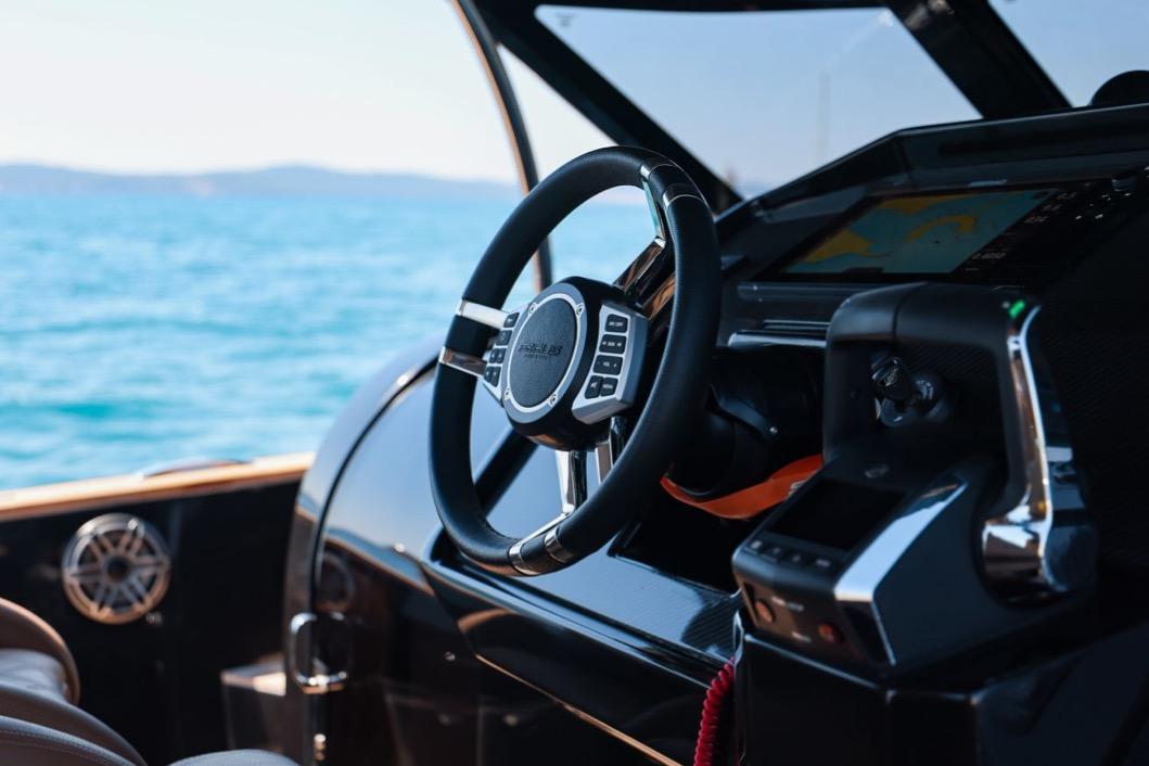 Steering wheel and dashboard of 2026 Focus FORZA 37 OB/FB boat on open water.