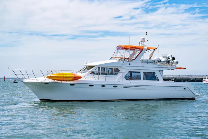 Altitude Adjustment Yacht Photos Pics Navigator 5300 Classic yacht from 2000 on calm water, featuring a vibrant orange canopy.