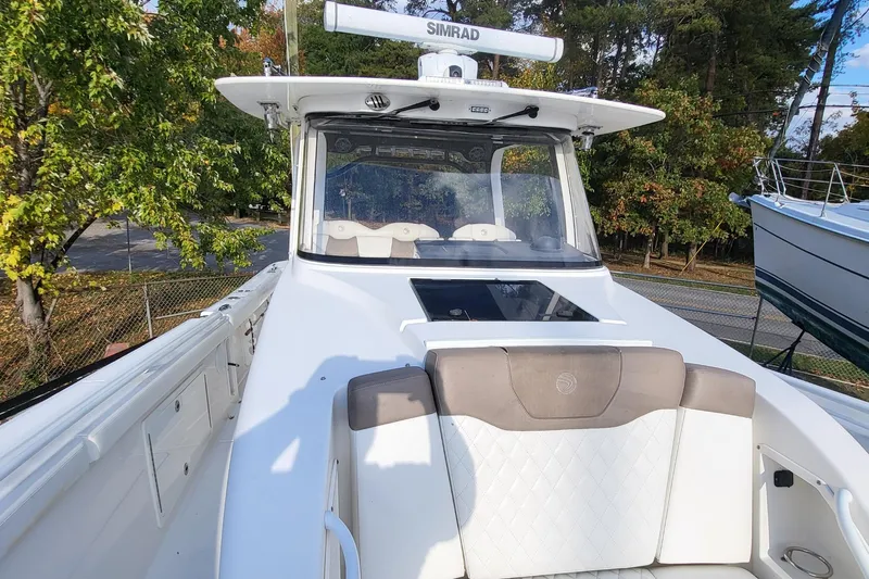  Yacht Photos Pics 2018 Edgewater 370CC boat with white seating and Simrad electronics, surrounded by trees.