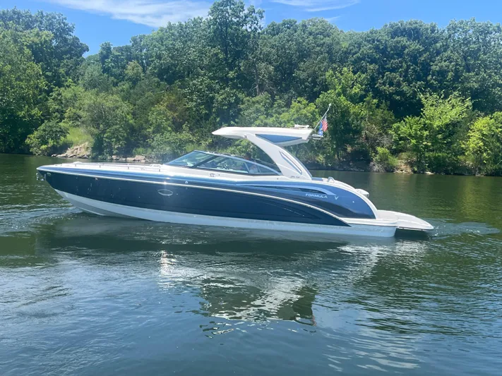  Yacht Photos Pics 2023 Formula 350 Crossover Bowrider I/O on a serene lake, surrounded by lush greenery.