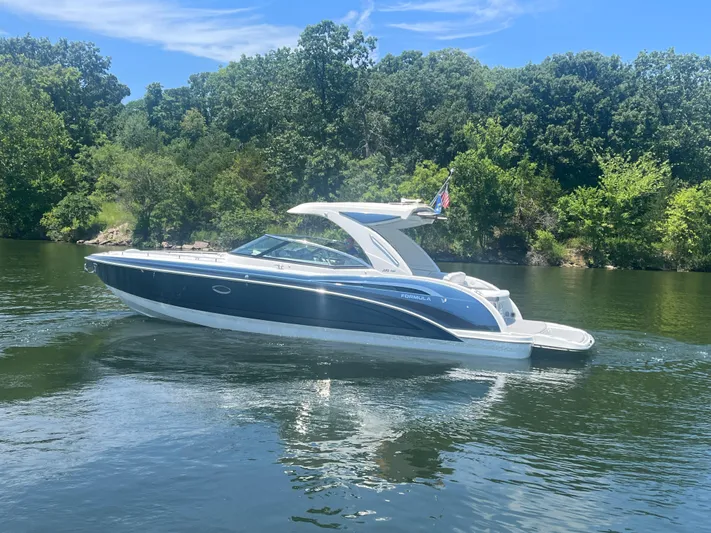  Yacht Photos Pics 2023 Formula 350 Crossover Bowrider I/O on a serene lake with lush greenery.