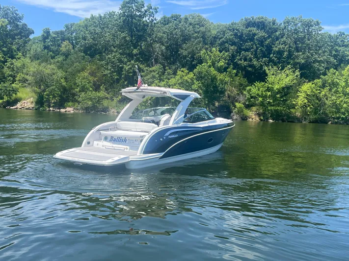  Yacht Photos Pics 2023 Formula 350 Crossover Bowrider I/O on a serene lake with lush greenery.