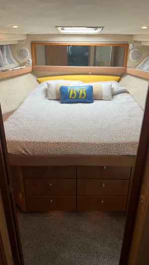 Yacht Photos Pics 1999 Bayliner 3988 Motoryacht bedroom with cozy bed, decorative pillows, and wooden storage drawers.