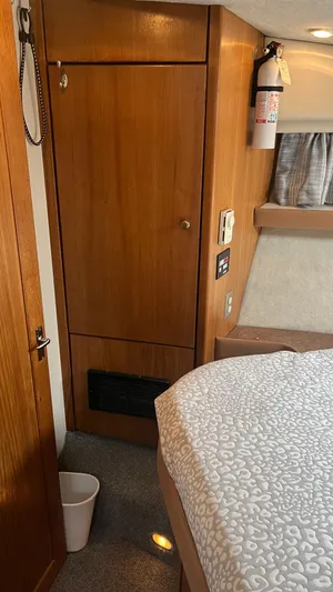  Yacht Photos Pics 1999 Bayliner 3988 Motoryacht interior with wood paneling, bed, and fire extinguisher.