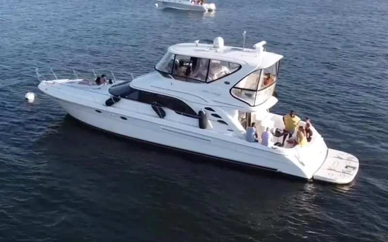  Yacht Photos Pics 2002 Sea Ray 56 Sedan Bridge yacht on calm water, with passengers enjoying the view.