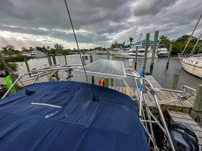 Three Dolphins Yacht Photos Pics 2005 Island Packet 370 sailboat docked, featuring solar panels and a blue canopy under cloudy skies.